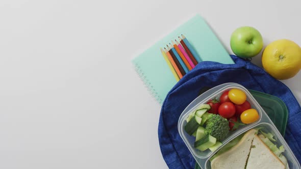 Video of healthy packed lunch of fruit and vegetables, with coloured pencils on schoolbag