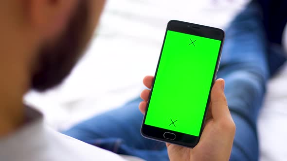 Black Smartphone with Green Screen for Chroma Key Compositing the Hands of a Man on Laptop