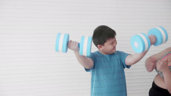 Asian family son fat exercise with dumbbell and mother cheer at home.