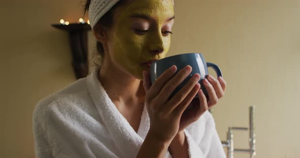 Relaxed biracial woman with face mask drinking coffee