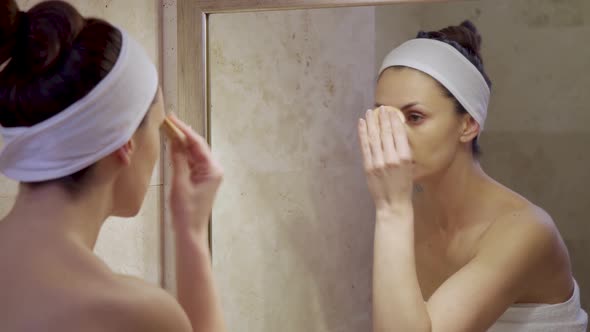 Beautiful Young Woman Doing Makeup Removal in the Mirror 