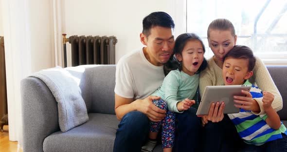 Happy family using digital tablet in living room