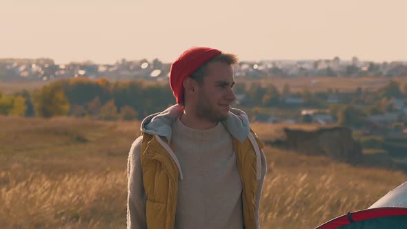 Smiling Guy Fixes Orange Hat and Walks Away on Yellow Meadow