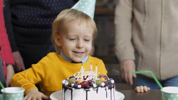 Excited Little Boy Blowing Candles on His Birthday