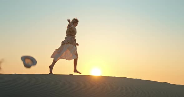 Woman Running By Sand Dune with Golden Sunset on Background