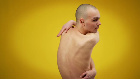 Young Man Hugging Himself Turning to Camera Posing at Yellow Background