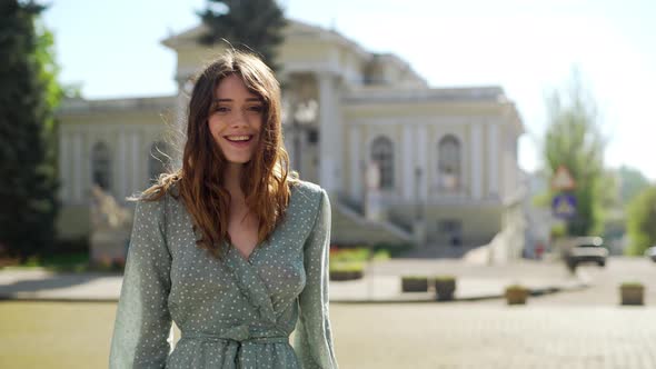 Portrait of Beautiful Joyful Woman 20s Wearing Dress Laughing While Walking in Downtown on Sunny Day