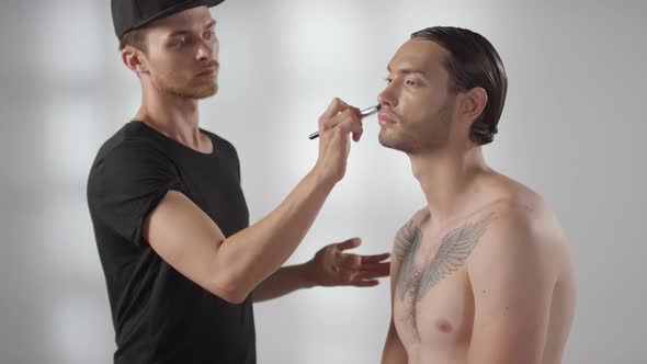 Make-Up Artist Applying Foundation on Face of Male Model