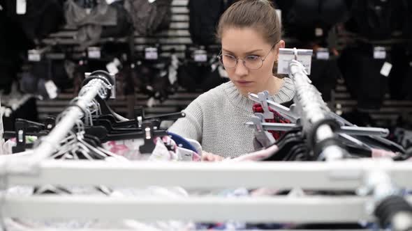 young woman with glasses is looking for the right clothes in the supermarket