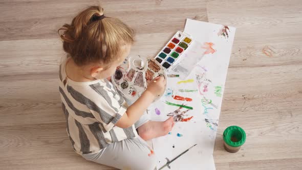 Small Cute Child Draws Colorful Paints on Paper Sitting in Living Room on Floor