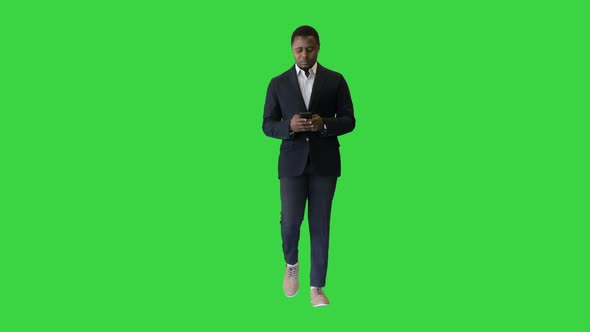 Confident Black Entrepreneur Walking and Using a Mobile Phone on a Green Screen Chroma Key