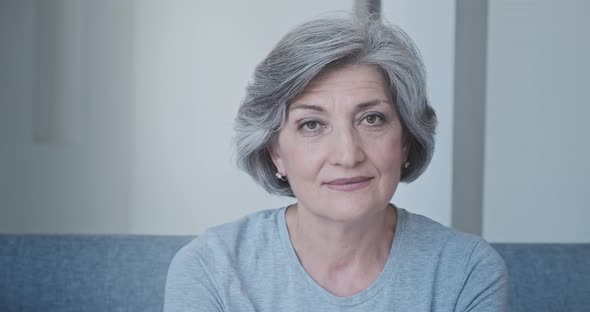 Closeup of Beautiful Intelligent Grandmother in Casual Clothes at Home Sitting on Couch