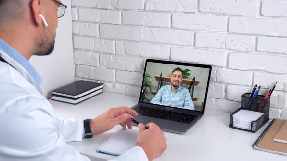 Doctor in Hospital Office Greets Tells Patient Online Video Call Webcam Laptop