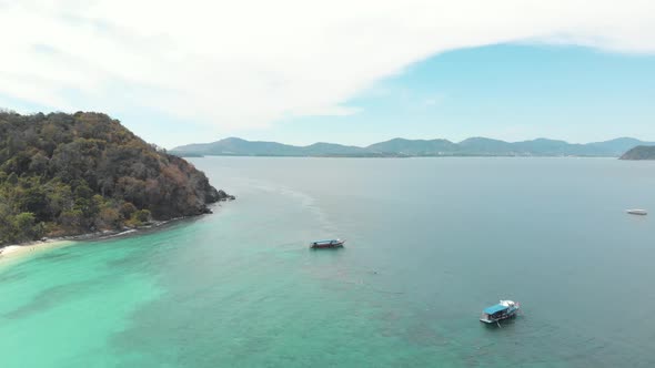 Idyllic coastline with tourist tour boats drifting above turquoise shallow sea in Koh Hey, Thailand