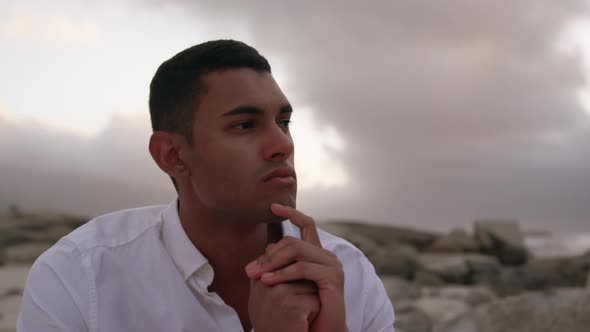 Man with hands on chin sitting on the beach 4k