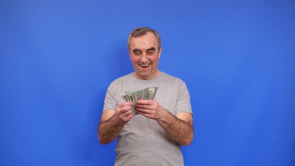 Happy Eldery Man Holding Bundle of Cash Dollars