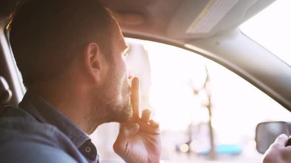 Handsome Bearded Man Smoking Cigarette While Driving in City with Sun Flare