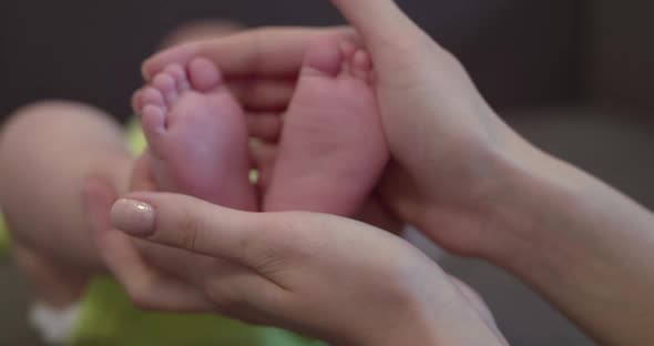 Mom's Hands Holds Baby's Cute Feet at Camera