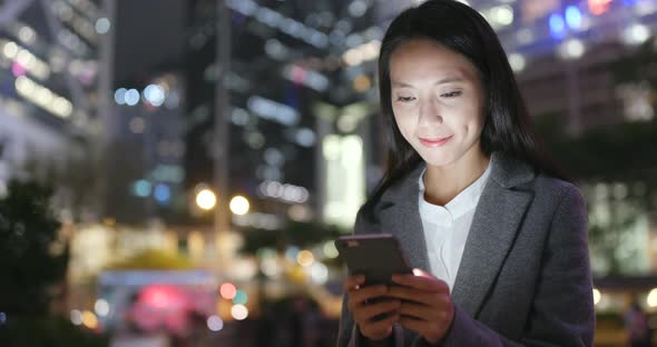 Business woman use of mobile phone in city at night