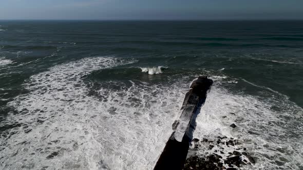 Passing over the Coquille River Jetty and across emerald green waters of the Pacific Ocean, aerial