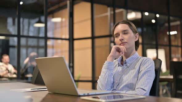 Young Woman Thinking While Relaxing At Work