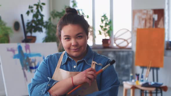 A Smiling Woman Paint Artist Looking in the Camera Being in the Drawing Studio