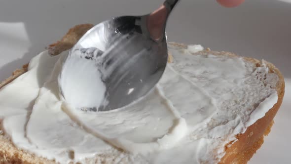 Cream cheese spreadin over the toast bread surface slow-mo video