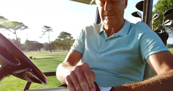 Golfer sitting in golf buggy wearing golf glove
