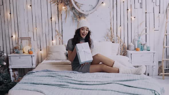 Portrait of a Young Woman Holding a Gift in Her Hand on the Bed.