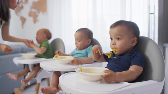 Three Asian Toddler Siblings in High Chairs Eating Puree