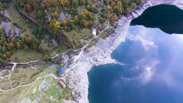 Lac d'Oô dam stone wall and keeper's cabin at artificial lake in the French Pyrenees with water stre