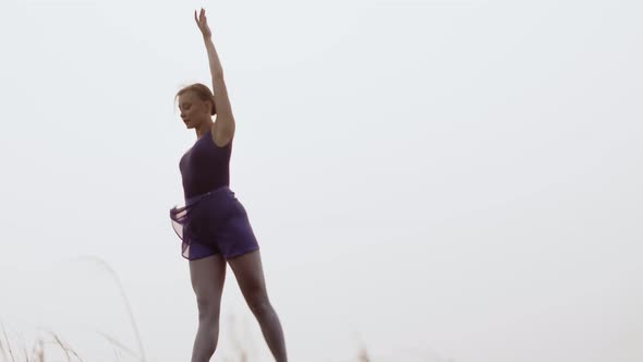 White caucasian woman dances a smooth dance, background of sky and sun.