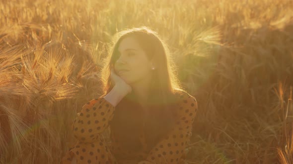 Pregnant woman in the rays of the sunset in the field