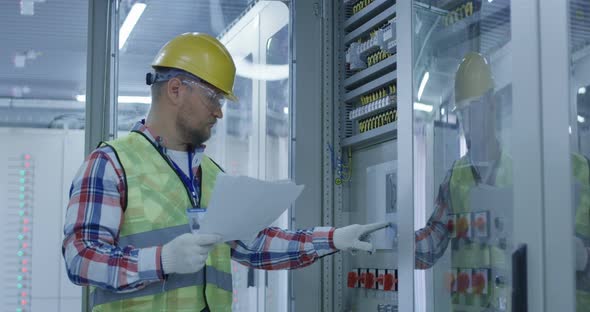 Electrical Worker Reading Paperwork and Inspecting Equipment