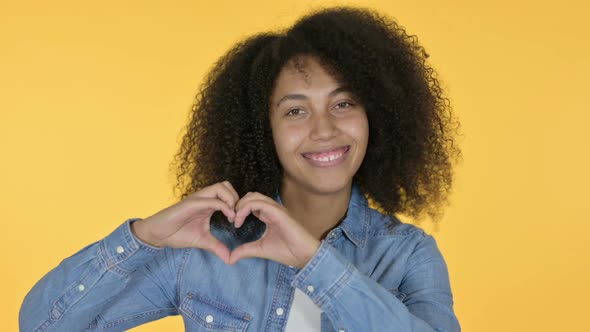 African Woman Heart Sign By Hand Yellow Background