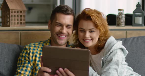 Young Couple Has a Video Chat on Tablet Computer, Showing V Signs, Close Up