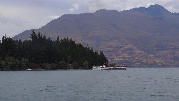 Wide shot of TSS Earnslaw arriving to Queenstown with Cecil's Peak behind. Lake Wakatipu, Queenstown