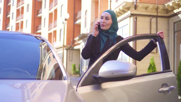 Muslim Woman in Hijab Talking on the Phone and Sits in the Car