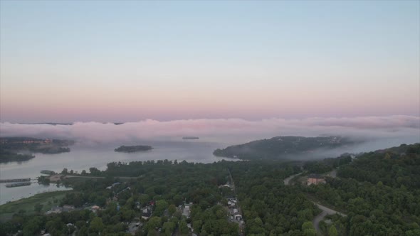 Time-lapse drone video of early morning fog on a lake at sunrise.