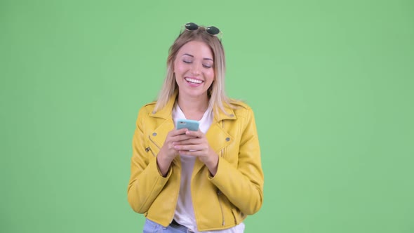 Happy Young Rebellious Blonde Woman Thinking While Using Phone