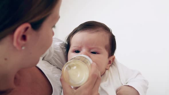 Mother bottle feeding baby girl