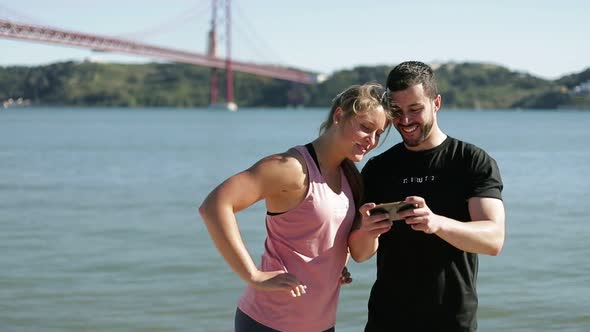 Two Sporty People Looking at Smartphone