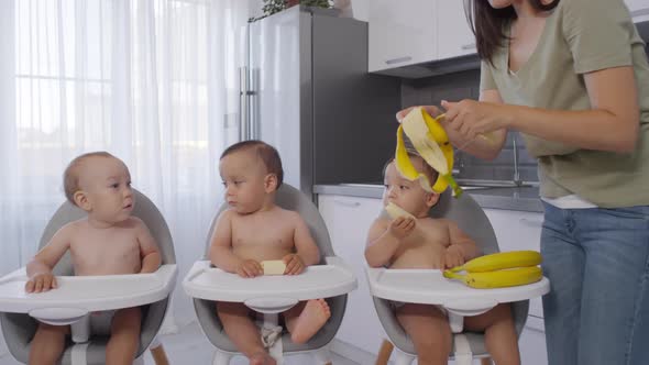 Asian Woman Peeling Bananas for Baby Triplets at Home