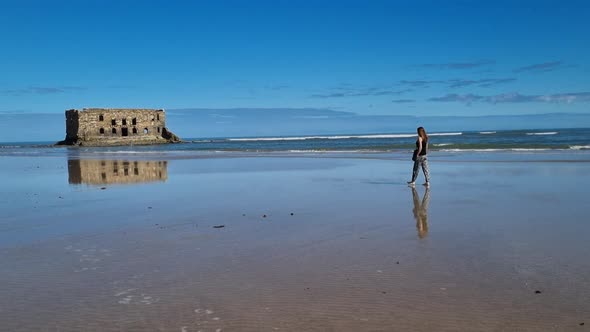 Girl with long hair walks towards the beach in Casa del mar, Tarfaya,, Marroco.  Elegant beautiful g