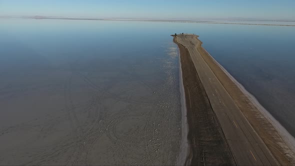 A drone shot flying over the Bonneville Salt Flats shows the Salt Flats causeway dividing the floode