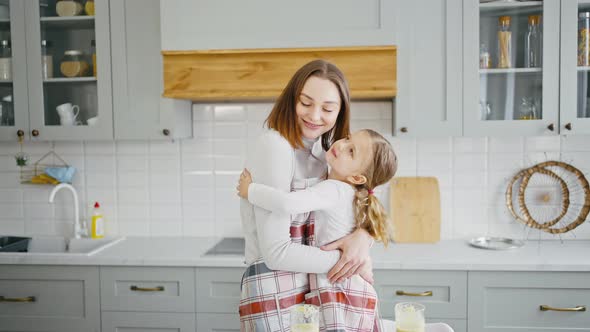 Adorable Little Girl Hugging with Her Mother and Laughing at Kitchen Little Boy Running Around Slow