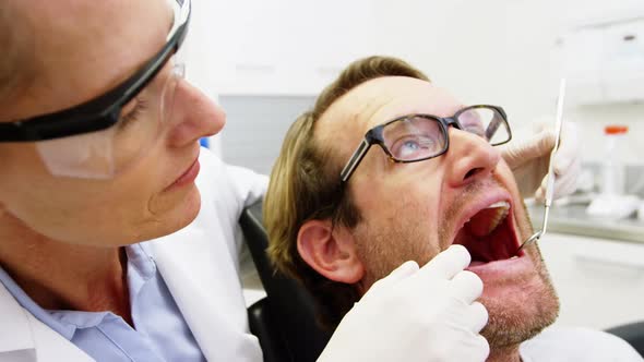 Female dentist examining male patient with tools