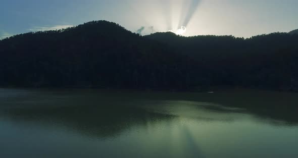 Afternoon drone shot of lake water and reflections revealing clouds and light rays