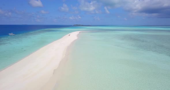 Daytime fly over clean view of a white sandy paradise beach and turquoise sea background in 4K