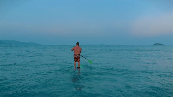 Ssurfer Is Waiting for His Wave To Surf, the Surfer Controls the Oar While Standing on the Surfboard